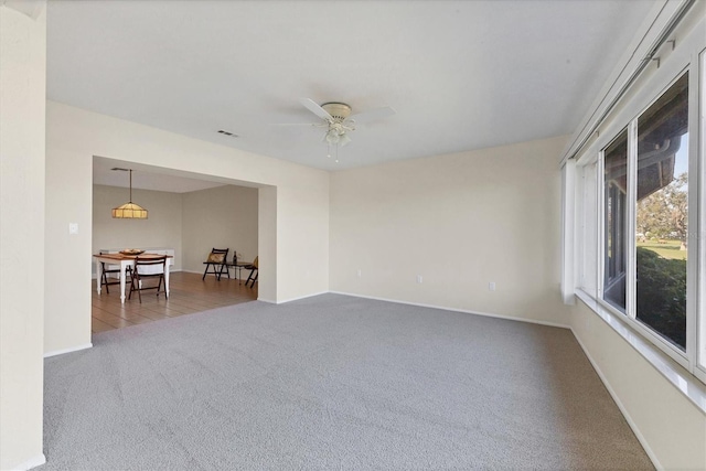 carpeted empty room with ceiling fan, visible vents, and baseboards