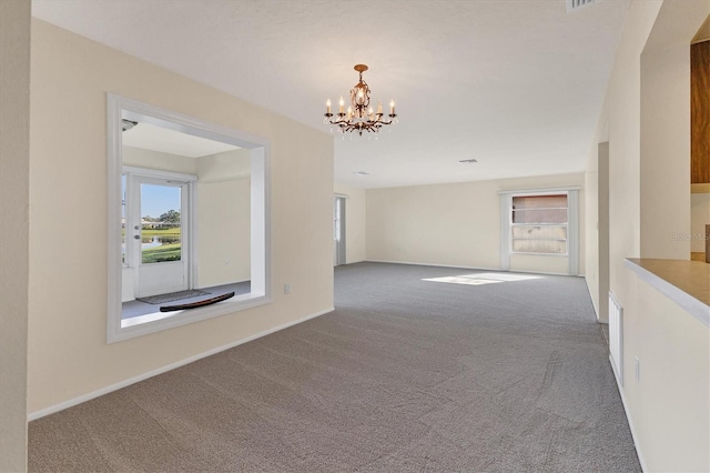 carpeted empty room with a chandelier and baseboards