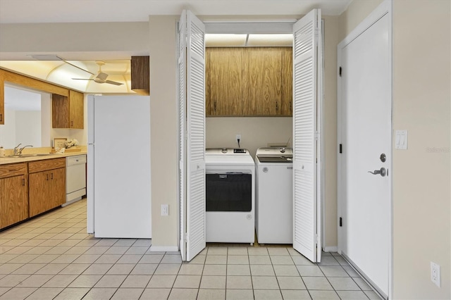 washroom featuring light tile patterned floors, a sink, baseboards, cabinet space, and washer and clothes dryer