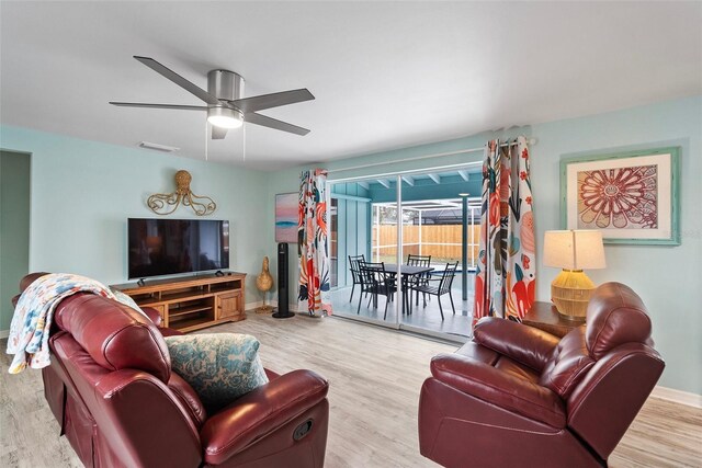 living area featuring visible vents, wood finished floors, a ceiling fan, and baseboards