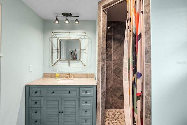 full bathroom with tiled shower, rail lighting, and vanity