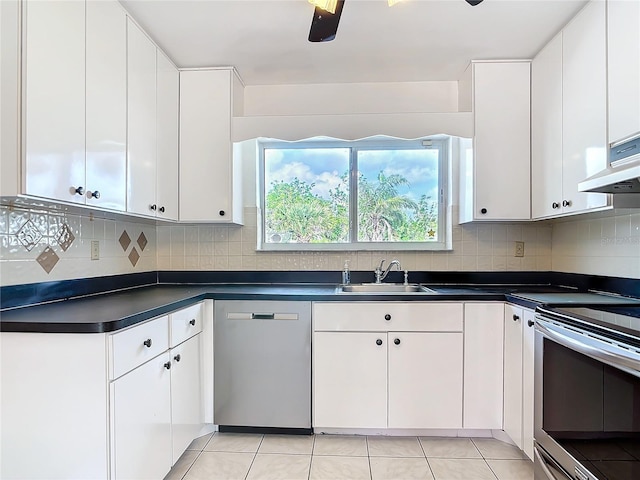 kitchen with appliances with stainless steel finishes, dark countertops, white cabinetry, and a sink