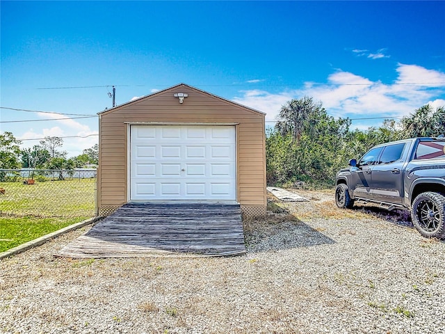 detached garage featuring driveway and fence