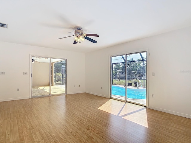 empty room featuring baseboards, plenty of natural light, and light wood-style floors