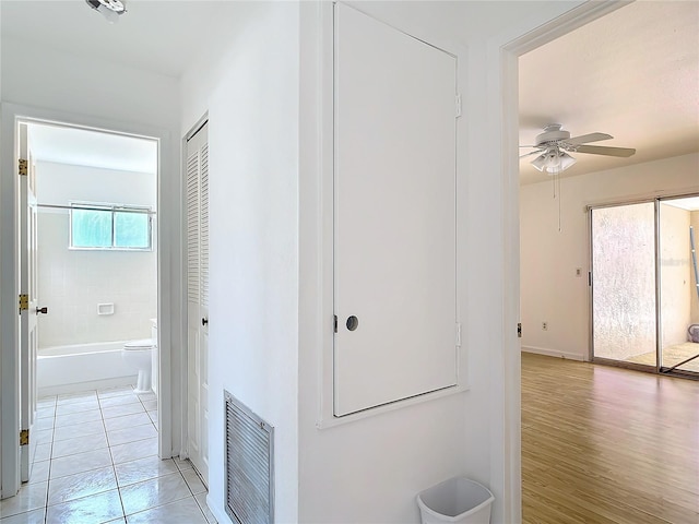 corridor with heating unit, light tile patterned floors, visible vents, and baseboards