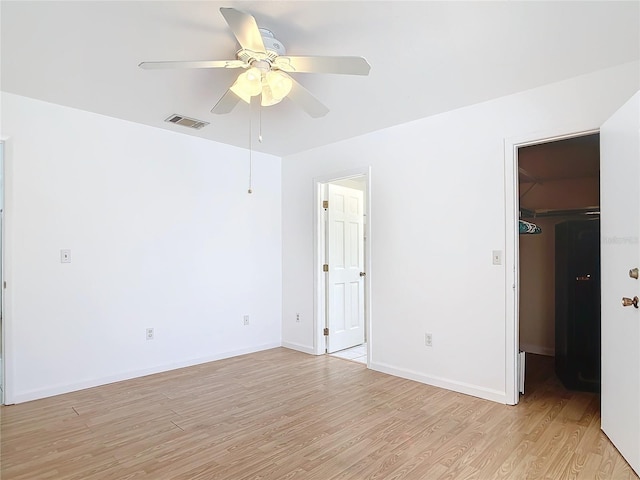 unfurnished room featuring light wood-style floors, baseboards, visible vents, and a ceiling fan