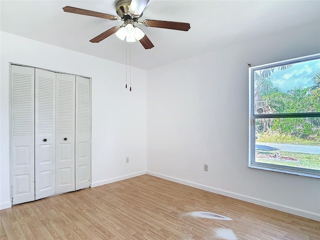 unfurnished bedroom with light wood finished floors, a closet, a ceiling fan, and baseboards