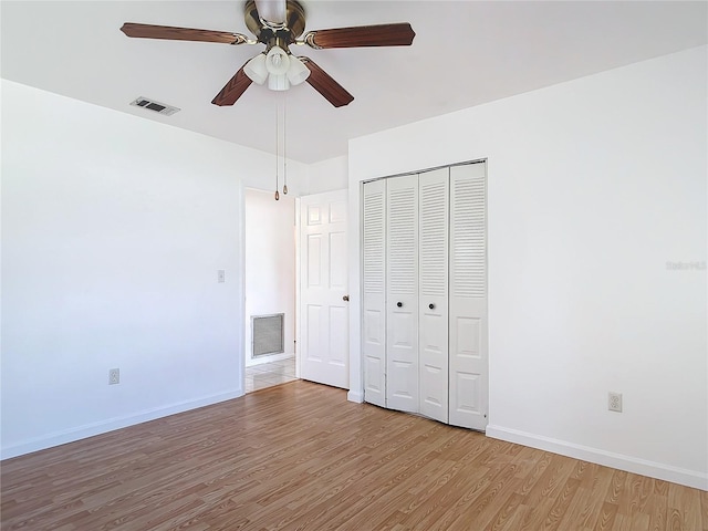 unfurnished bedroom featuring a closet, visible vents, baseboards, and wood finished floors