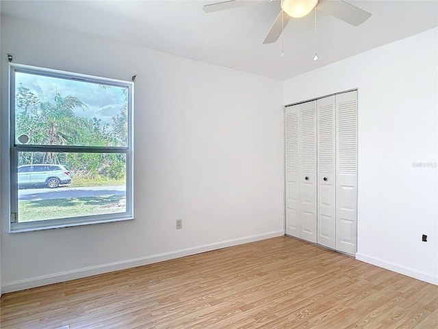 unfurnished bedroom featuring a closet, baseboards, ceiling fan, and light wood finished floors