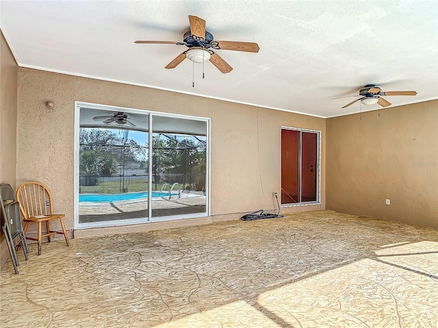 spare room with a ceiling fan, a textured wall, and a textured ceiling