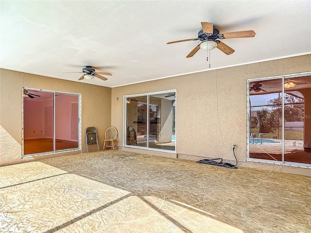 interior space with a textured ceiling, a textured wall, and a ceiling fan