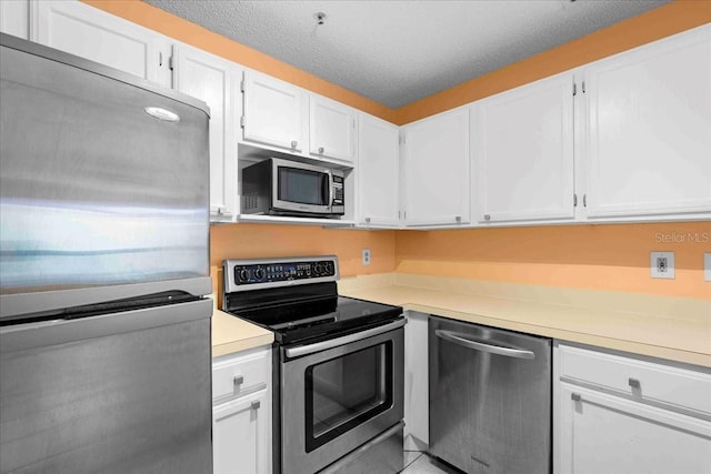 kitchen featuring a textured ceiling, light countertops, appliances with stainless steel finishes, and white cabinets