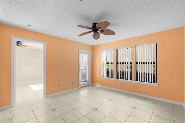 unfurnished room with a textured ceiling, ceiling fan, light tile patterned floors, and baseboards