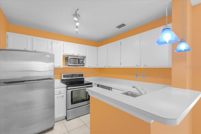 kitchen with stainless steel appliances, light countertops, white cabinetry, and pendant lighting