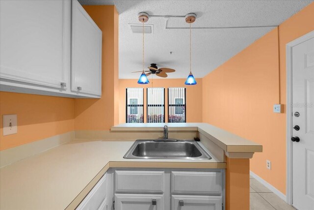 kitchen featuring a peninsula, white cabinetry, light countertops, and decorative light fixtures