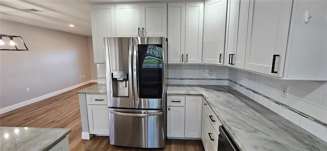 kitchen featuring light stone countertops, stainless steel fridge, and white cabinets