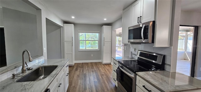 kitchen featuring appliances with stainless steel finishes, white cabinets, and light stone counters