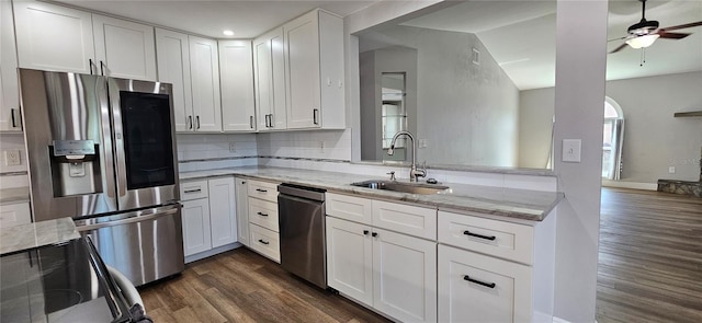 kitchen featuring light stone counters, dark wood finished floors, stainless steel appliances, white cabinets, and a sink