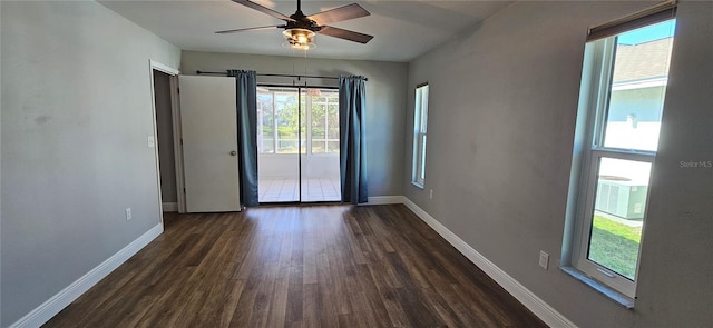 empty room with a ceiling fan, dark wood finished floors, and baseboards