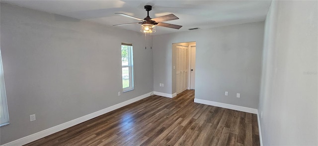 unfurnished room with ceiling fan, baseboards, visible vents, and dark wood finished floors