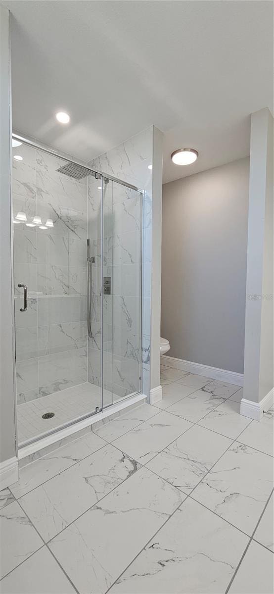 full bathroom with toilet, marble finish floor, a marble finish shower, and baseboards