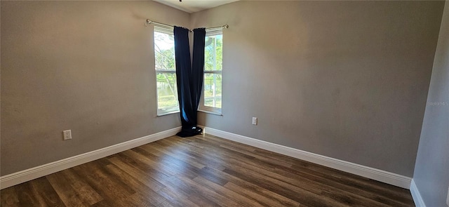 empty room featuring dark wood-style floors, plenty of natural light, and baseboards