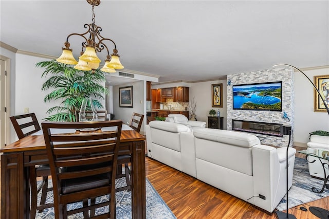 living room featuring ornamental molding, visible vents, a fireplace, and wood finished floors