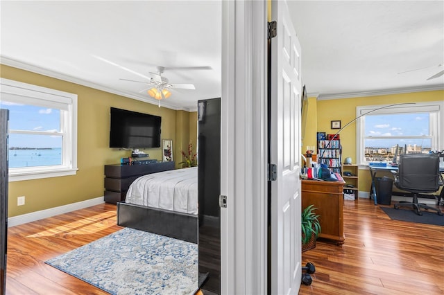 bedroom featuring baseboards, wood finished floors, a ceiling fan, and crown molding