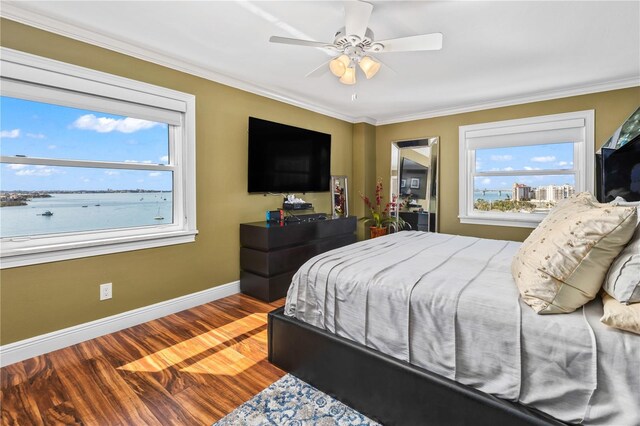 bedroom with ornamental molding, multiple windows, baseboards, and wood finished floors