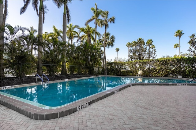 community pool with a patio area and fence