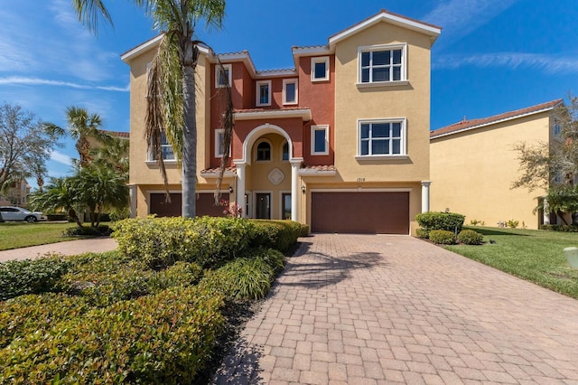 mediterranean / spanish-style home featuring a garage, a tiled roof, decorative driveway, and stucco siding