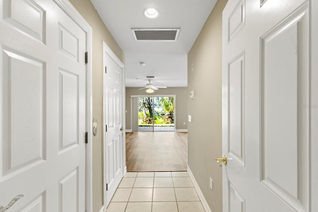 hallway with visible vents, baseboards, and light tile patterned flooring