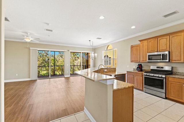 kitchen featuring light stone counters, a kitchen island with sink, visible vents, ornamental molding, and appliances with stainless steel finishes