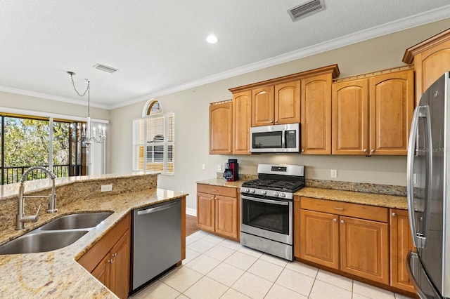 kitchen with light stone counters, a sink, visible vents, ornamental molding, and appliances with stainless steel finishes