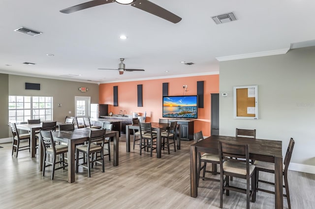 dining space with light wood-type flooring, baseboards, visible vents, and crown molding