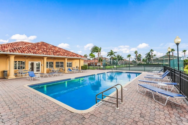 community pool featuring french doors, fence, and a patio