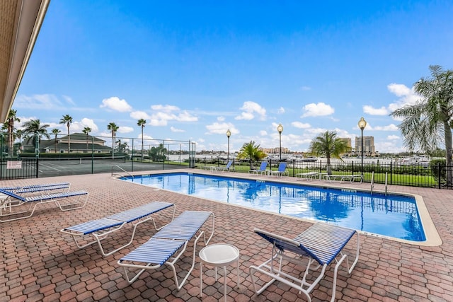 pool with a patio area and fence