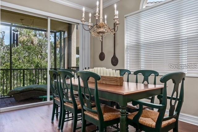 dining room with a chandelier, ornamental molding, wood finished floors, and baseboards