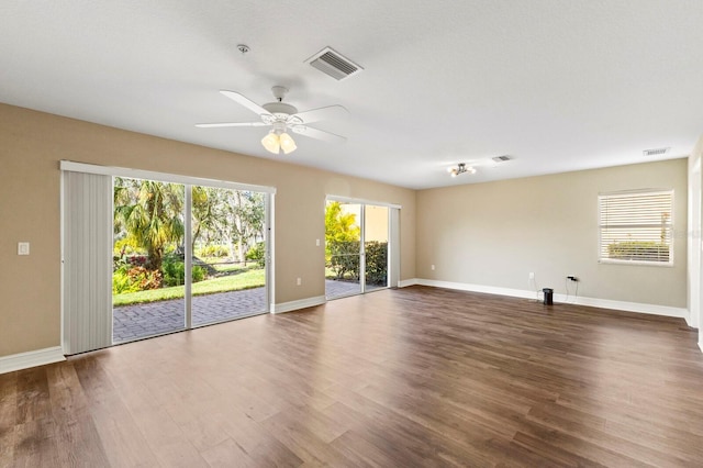 empty room with ceiling fan, wood finished floors, visible vents, and baseboards