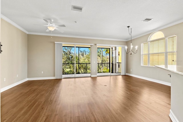 empty room featuring visible vents, crown molding, baseboards, and wood finished floors