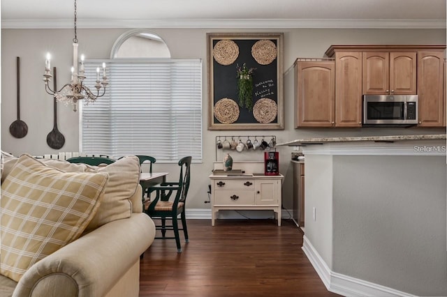 kitchen with baseboards, dark wood-style floors, stainless steel microwave, ornamental molding, and an inviting chandelier