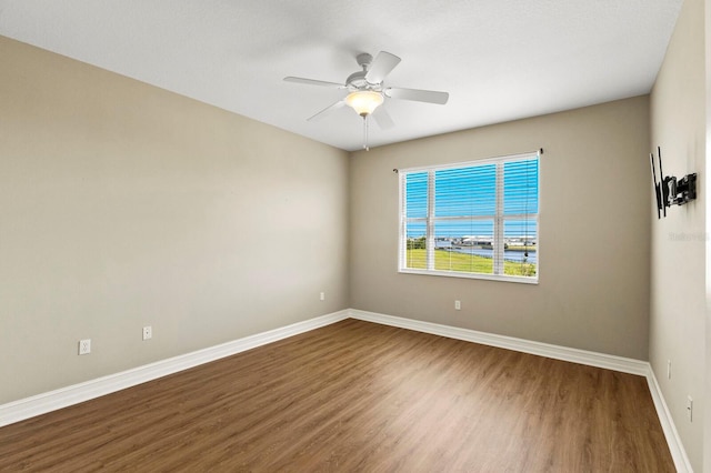 spare room with a ceiling fan, baseboards, and wood finished floors