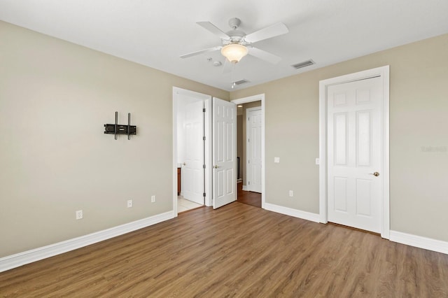 unfurnished bedroom with connected bathroom, wood finished floors, visible vents, and baseboards