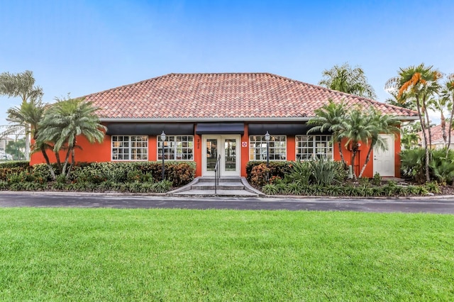 view of front facade with a tiled roof, french doors, a front lawn, and stucco siding