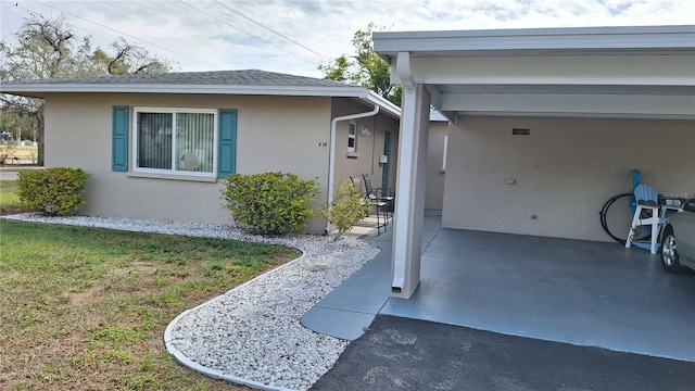 property entrance featuring a yard, a shingled roof, a carport, and stucco siding