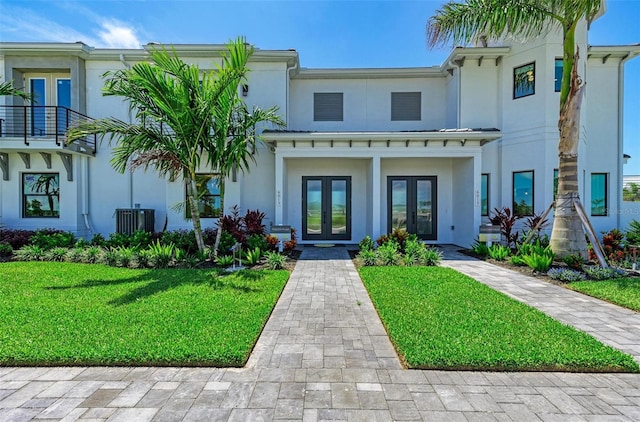 view of front facade with stucco siding, a front yard, and french doors