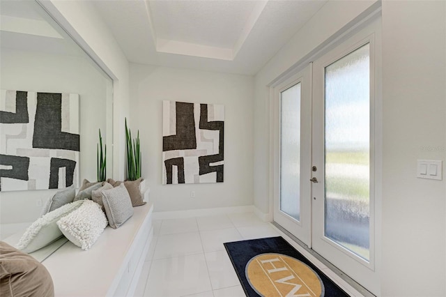 interior space featuring light tile patterned floors, baseboards, a tray ceiling, and french doors