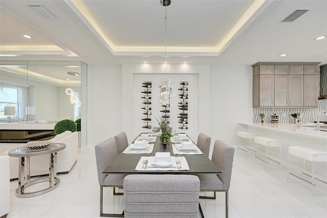 dining space with light tile patterned floors, a tray ceiling, and visible vents