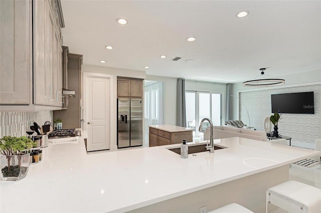 kitchen with a peninsula, stainless steel fridge, light countertops, and a sink