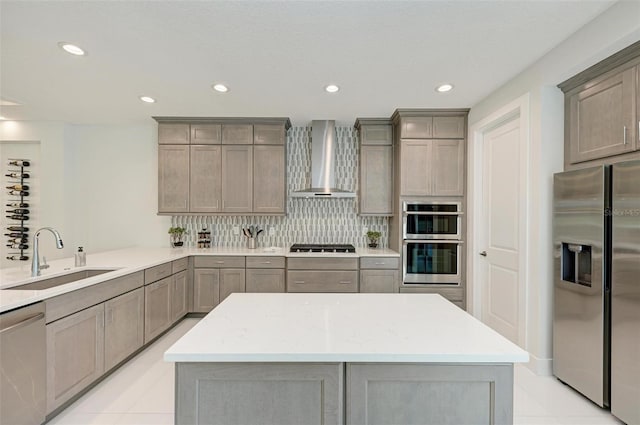 kitchen featuring stainless steel appliances, backsplash, a sink, wall chimney range hood, and a peninsula